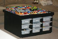 a toy chest sitting on top of a couch next to a stuffed animal and plastic bins