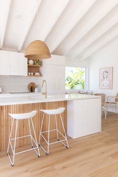 two white stools are in front of the kitchen island and countertop with an island