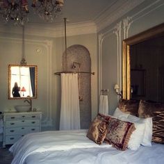 a white bed sitting in a bedroom next to a mirror