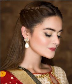 a woman with long brown hair wearing a red and gold sari dress, holding a white flower in her left hand