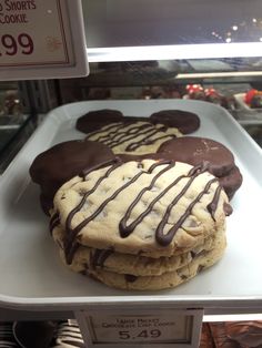 cookies with chocolate drizzled on them in a display case at a bakery