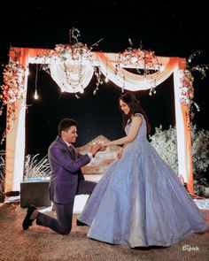 a man kneeling down next to a woman in a blue dress on top of a stage