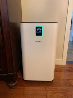 a white air purifier sitting on top of a wooden floor next to a wall