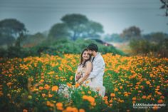 a man and woman are hugging in a field of flowers