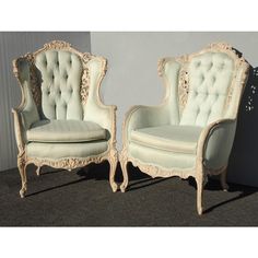 two white chairs sitting next to each other on top of a carpeted floor in front of a wall