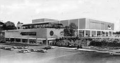 an old black and white photo of a building with cars parked in front of it