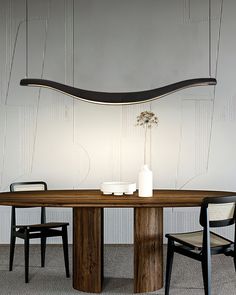 a wooden table with two chairs and a vase on it in front of a white wall