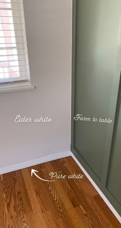 the corner of a room with wood flooring and glass doors that have been painted white