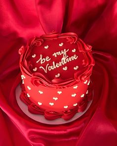 a red cake with white hearts on it and the words be my valentine written on top