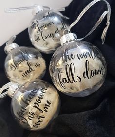 four glass ornaments with handwritten words on them