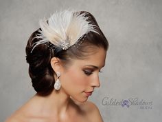 a woman in a wedding dress wearing a feathered headpiece with pearls on it