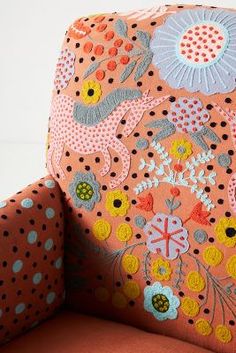 an upholstered orange chair with colorful flowers and polka dots on the backrest