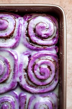 a pan filled with purple rolls covered in icing