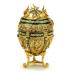 an ornately decorated gold and green urn with two birds on the top,