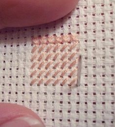 a close up of a person's hand with some stitches on the table cloth