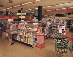 an old photo of people shopping in a grocery store with signs hanging from the ceiling