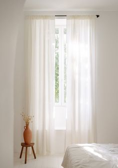 a bedroom with white walls and flooring has a large window that is open to the outside