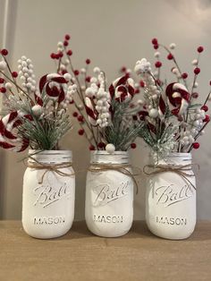 three mason jars with red and white flowers in them