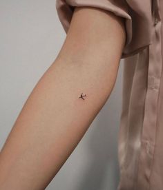 a small airplane tattoo on the left inner arm and wrist is shown in black ink