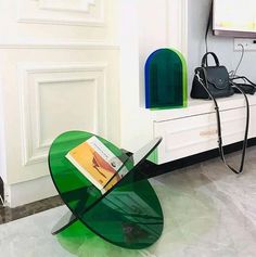 a green table sitting on top of a white floor next to a black handbag