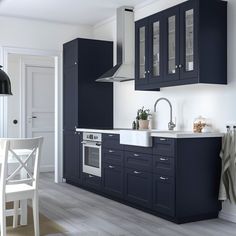 a modern kitchen with dark blue cabinets and white counter tops, along with a dining room table