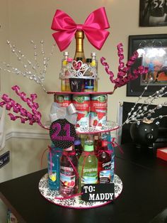 a birthday cake made to look like a tower with liquor bottles on top and pink bows