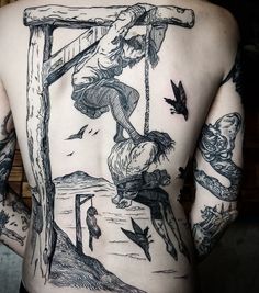 a man with tattoos on his back is holding a cross and birds flying around him