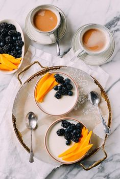 two bowls filled with yogurt and fruit on top of a marble countertop