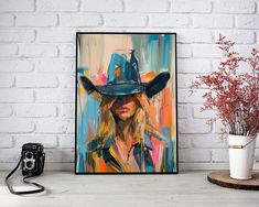 a painting of a woman wearing a cowboy hat on a wall next to a camera