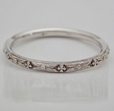 a silver ring with flowers and leaves on the inside, sitting on a white surface