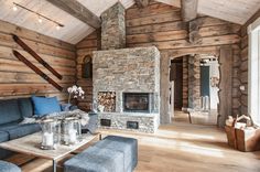 a living room filled with furniture and a fire place next to a wooden wall covered in logs