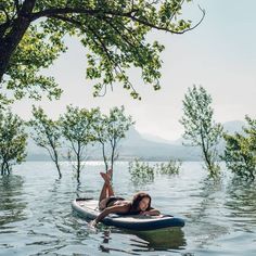 a woman laying on top of a surfboard in the middle of a flooded area