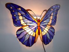 a stained glass butterfly lamp hanging on the wall