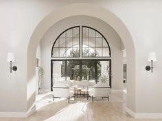 an arched doorway leads into a white living room