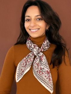 Model wearing the block printed Lana bandana tied around the neck against a brown background Casual Winter Headscarf One Size, Casual Winter Headscarf, One Size, Casual Fall Scarves, Bohemian Cotton Bandana As Gift, Bohemian Cotton Bandana Gift, White Bohemian Scarf For Fall, Casual One Size Bandana For Gift, Traditional White Winter Scarves, Traditional White Scarves For Winter