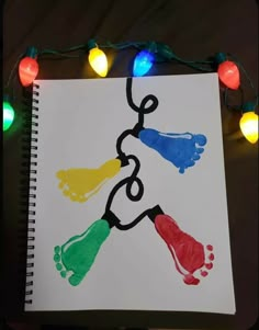 a hand and foot print on a sheet of paper with christmas lights around the edges