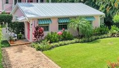 a pink house in the middle of a lush green yard