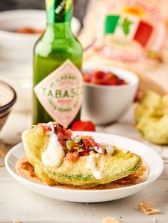 an omelet is sitting on a plate next to a bottle of tabasco