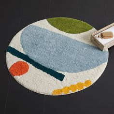 a round rug with an abstract design on it and a remote control next to it