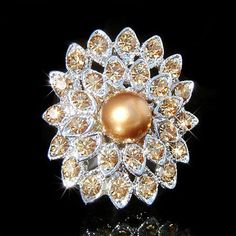 a gold and white flower brooch with crystal stones on the center, in front of a black background