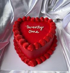 a red heart shaped cake with the words twenty one written on it in cursive writing