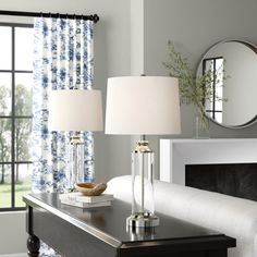 two lamps are sitting on a table in front of a mirror and window with blue curtains