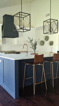 a kitchen with two bar stools next to an island in the middle of it