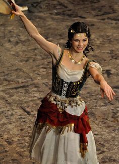 a woman in an ancient costume is holding a frisbee and smiling at the camera