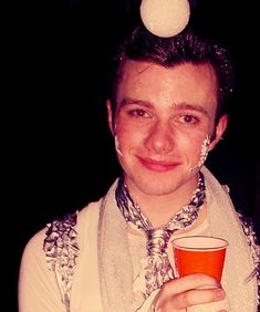 a person with a scarf around their neck holding a cup and a ball on his head