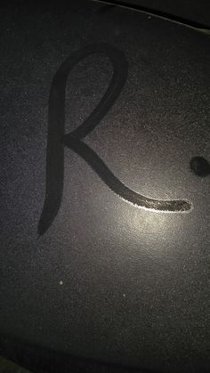 the letter k is drawn on top of a shiny surface with a black shadow over it