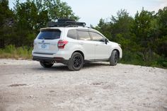 a white suv parked on top of a dirt road