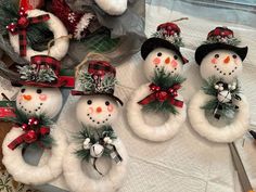 four snowmen with hats and scarfs are sitting on a table next to other christmas decorations