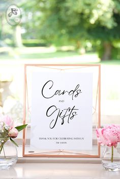 a card and gifts sign sitting on top of a table next to vases with flowers