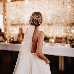 the back of a bride's dress is shown in front of a table with candles